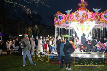 udekorowany skwer, scena, występy, osoby biorące udział w spotkaniu, poczęstunek, karuzela, żywa szopka