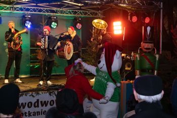 udekorowany skwer, scena, występy, osoby biorące udział w spotkaniu, poczęstunek, karuzela, żywa szopka