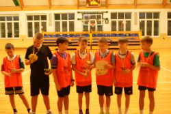 Siedmiu chłopców w strojach sportowych z medalami na szyjach. Jeden z nich trzyma puchar i dyplom.