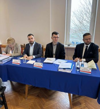 trzech burmistrzów przy stole konferencyjnym obok skarbnik miasta