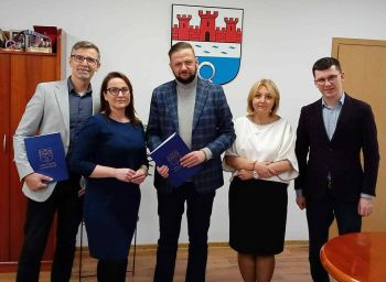 osoby pozujące do zdjęcia, dwóch mężczyzn trzyma teczki gratulacyjne