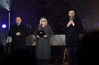 Ksiądz, kobieta i mężczyzna z mikrofonem stojący w kościele.