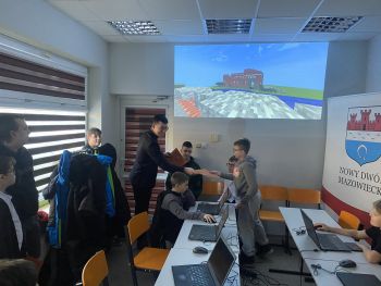 sala z rzutnikiem, burmistrz wręcza dyplomy dzieciom