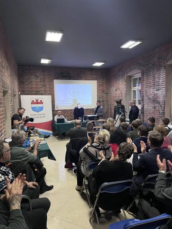 wykład w murach muzeum, zebrani wysłuchujący wykładu, prezentacja wyświetlana na ścianie