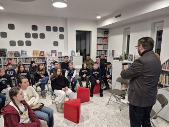 sala w bibliotece, zebrana młodzież siedzi na krzesełkach,