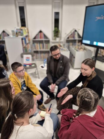 sala w bibliotece, zebrana młodzież siedzi na krzesełkach,
