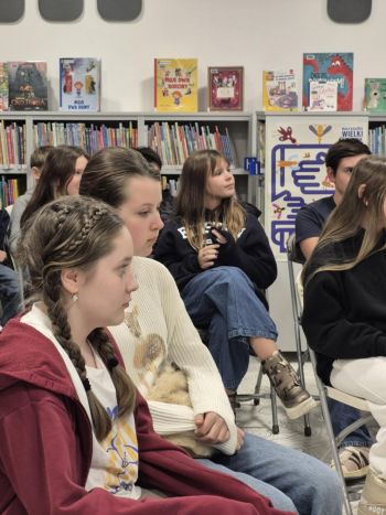 sala w bibliotece, zebrana młodzież siedzi na krzesełkach,