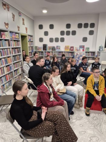 sala w bibliotece, zebrana młodzież siedzi na krzesełkach,