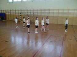 Dziewczynki w strojach sportowych na sali gimnastycznej.