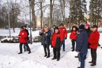 Kobiety i mężczyźni w ubraniach zimowych stojący na śniegu w parku.