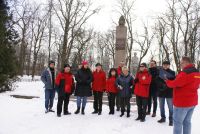 Kobiety i mężczyźni w ubraniach zimowych stojący przed Pomnikiem Obrońców Modlina.