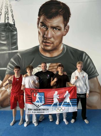 grupa bokserów pozujących do zdjęcia, trzymają flagę klubową