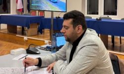 prowadzący spotkanie, w tle monitor z wyświetloną prezentacją