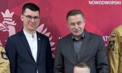 zgromadzona młodzież w strojach czarnych strojach pożarniczych, wręczanie nagród, w tle czerwona ścianka straży pożarnej