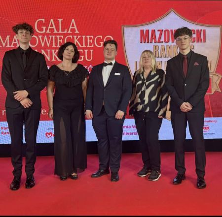 uczniowie wraz z nauczycielami pozują do zdjęcia, wszyscy w galowych strojach