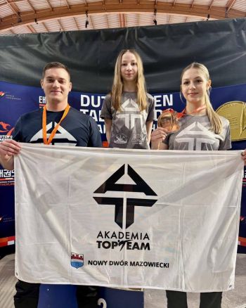 wspólne zdjęcie zawodniczek z trenerem, razem trzymają flagę klubową