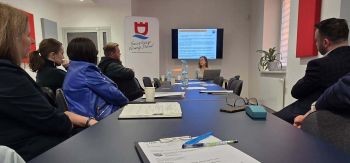 stół konferencyjny przy którym siedzą zebrani na spotkaniu,