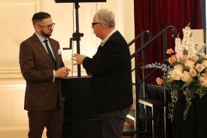 Dwóch stojących mężczyzn w okularach rozmawiających ze sobą.