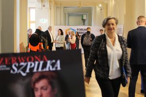 Grupa osób na korytarzu.