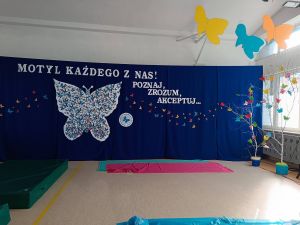 Różnokolorowe motyle na ściance, pod sufitem i na gałązkach drzewek.