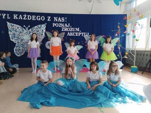 Chłopiec i osiem dziewczynek z motylimi skrzydełkami na plecach.