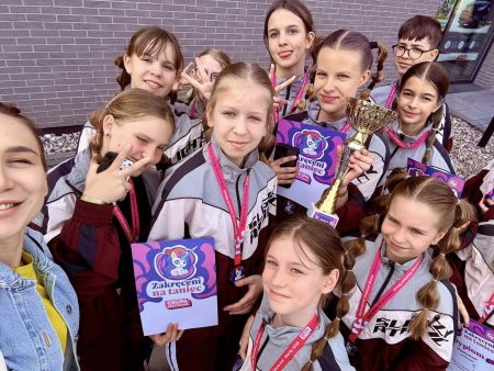 grupa zawodników trzyma puchar