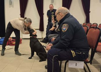 kobieta mówi do czarnego psa, obok strażnicy miejscy