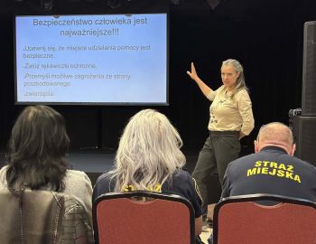 w tle prezentacja, kobieta z podniesiona ręką omawia temat