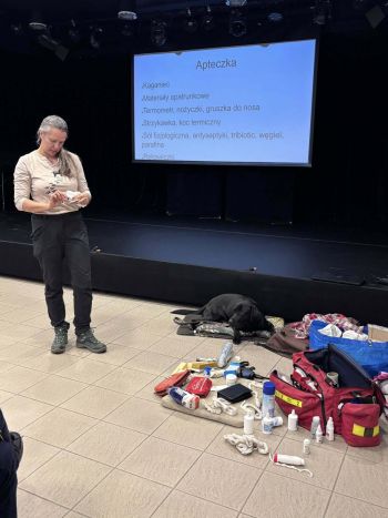 na podłodze leży czarny pies, obok wyłożona zawartość apteczki