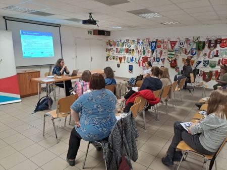 sala konferencyjna, na krzesłach siedzą zaproszeni goście, na ścianie wyświetlona prezenacja