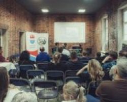 sala w muzeum, na krzesełkach siedzą zebrani uczestnicy wydarzenia