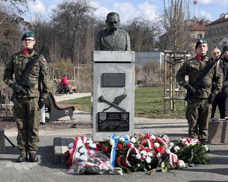 popiersie Józefa Piłsudskiego, po dwóch bokach stoją żołnierze, pod pomnikiem biało czerwone kwiaty