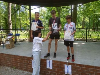 teren parku w Twierdzy Modlin, zawodnicy w strojach sportowych, wspólne zdjęcie z medalami, zwycięzcy na podium