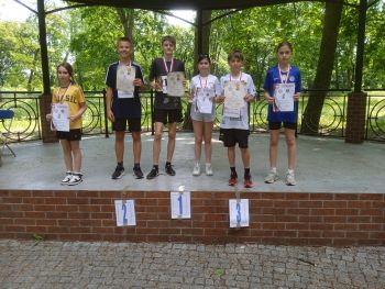 teren parku w Twierdzy Modlin, zawodnicy w strojach sportowych, wspólne zdjęcie z medalami, zwycięzcy na podium
