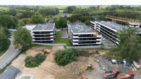 zdjęcie z drona, widok na osiedle, plac budowy, koparki i spychacze usuwające drzewa