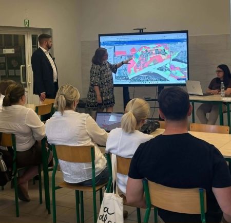 kobieta stojąca przy ekranie patrzy na wyświetlana mapę