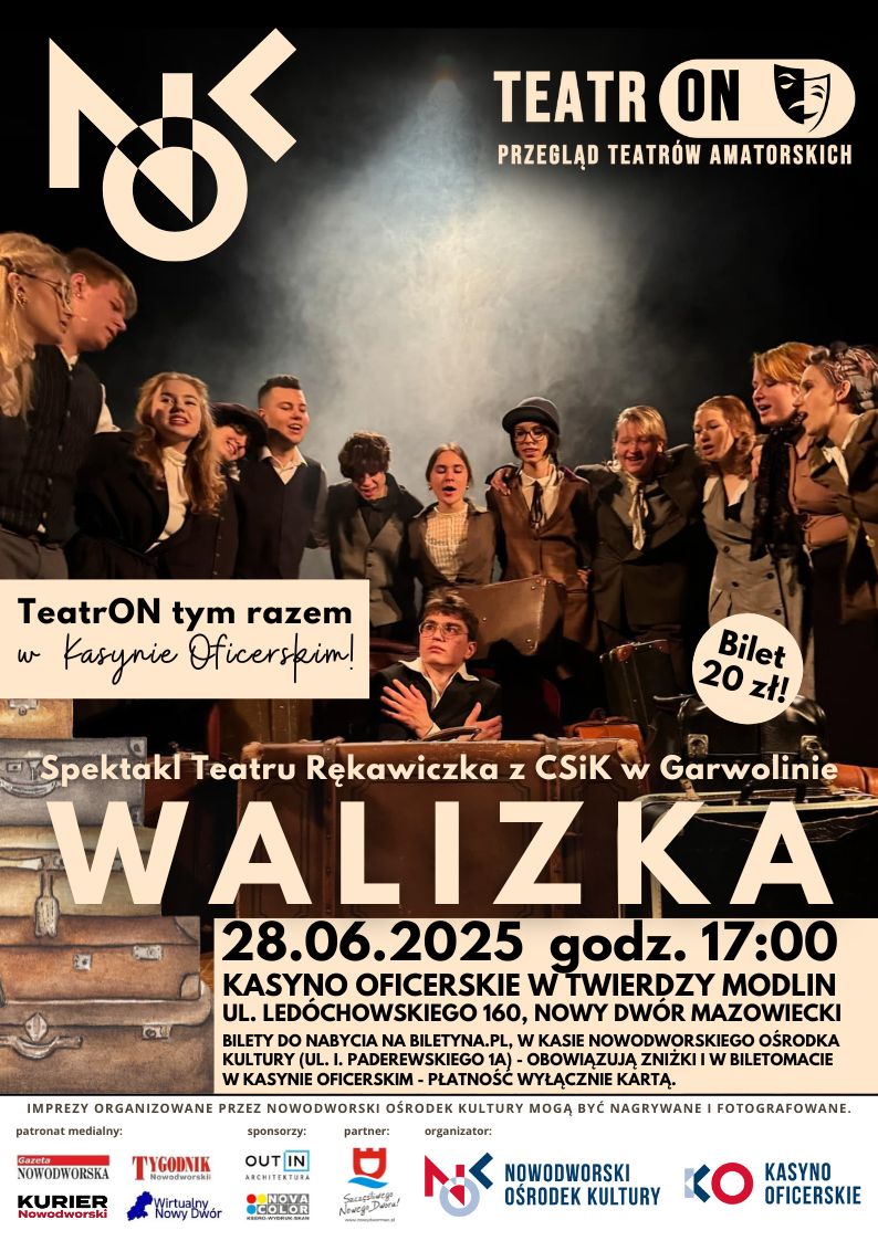 Kilkanaście osób zebranych wokół siedzącego mężczyzny z walizką.