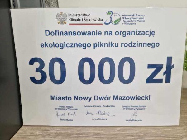 Symboliczny czek przekazany przez Wojewódzki Fundusz Ochrony Środowiska i Gospodarki Wodnej dla Miasta Nowy Dwór Mazowiecki na organizację Ekologicznego Pikniku Rodzinnego, z informacją o udzieleniu dofinansowania w wysokości 30 000 zł.