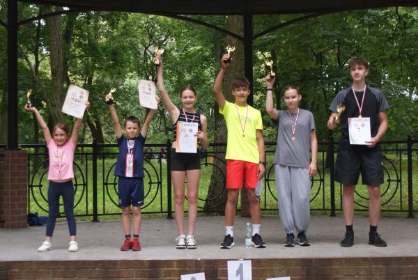 Trzy dziewczynki i trzech chłopców z medalami na szyjach oraz pucharami i dyplomami w rękach.
