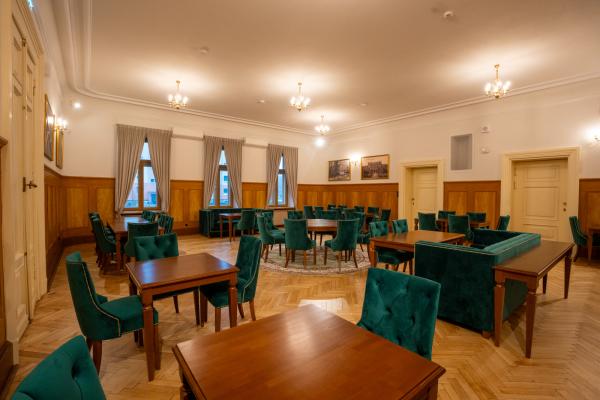 Jeden okrągły i 6 prostokątnych drewnianych stołów. Przy każdym z nich welurowe krzesła. Przy dwóch także sofa.