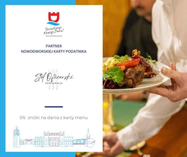 Osoba trzymająca w dłoni talerz z mięsem i warzywami.