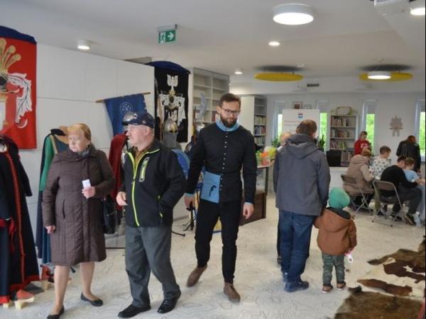 Grupa ludzi w sali z zabytkowymi strojami i oprawionymi skórami zwierząt.