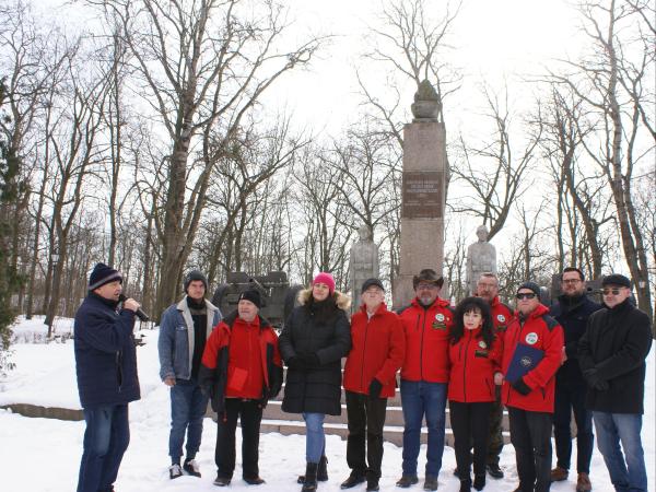 Kobiety i mężczyźni w ubraniach zimowych stojący przed Pomnikiem Obrońców Modlina.