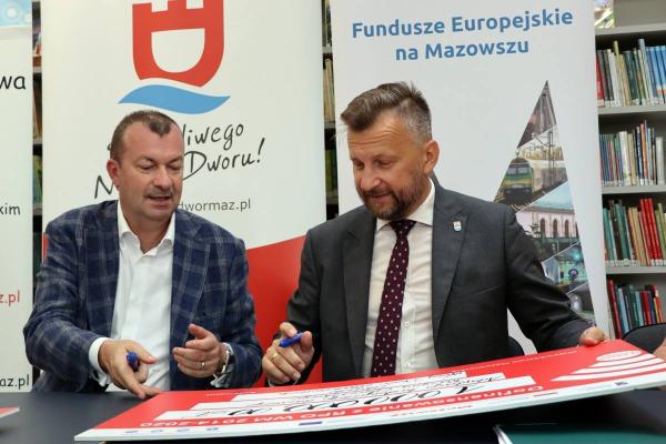 Burmistrz Jacek Kowalski i Wicemarszałek Województwa Mazowieckiego Wiesław Raboszuk podpisują czeki.